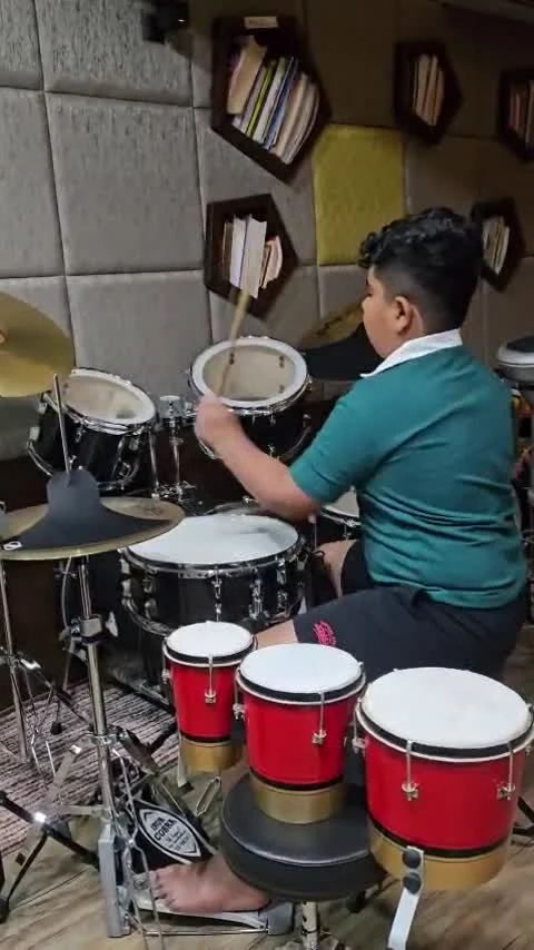 Hridan playing an acoustic drum kit in the studio